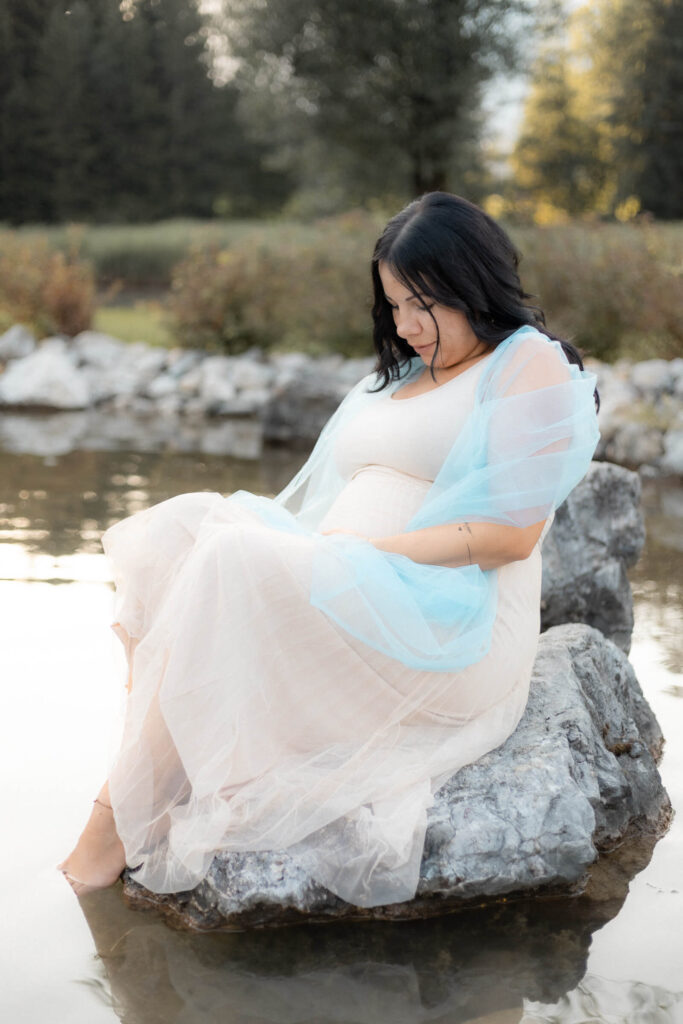 Babybauchshooting mit Mama die auf dem stein Sitz in einem Kneipbad